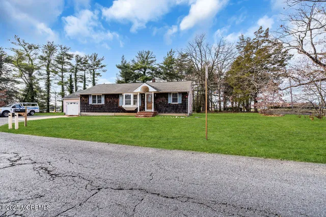 a view of house with a big yard and large trees