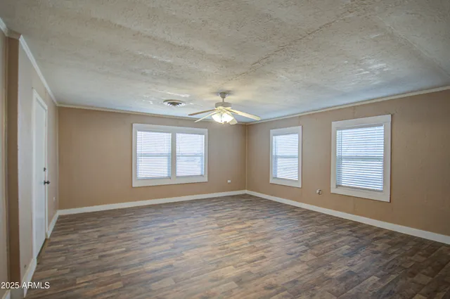a view of an empty room with a window and wooden floor