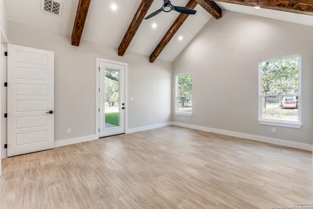 an empty room with wooden floor cabinet and windows