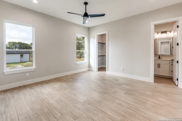 a view of an empty room with a window and wooden floor
