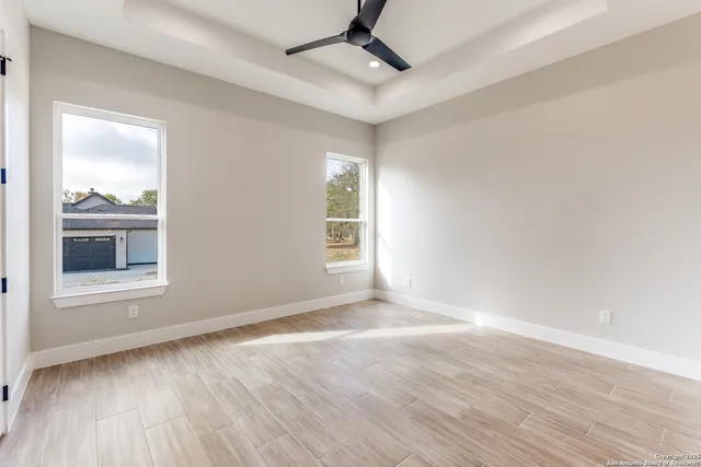 a view of an empty room with wooden floor and a window
