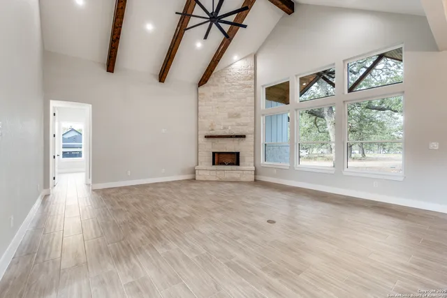 a view of an empty room with wooden floor fireplace and a window