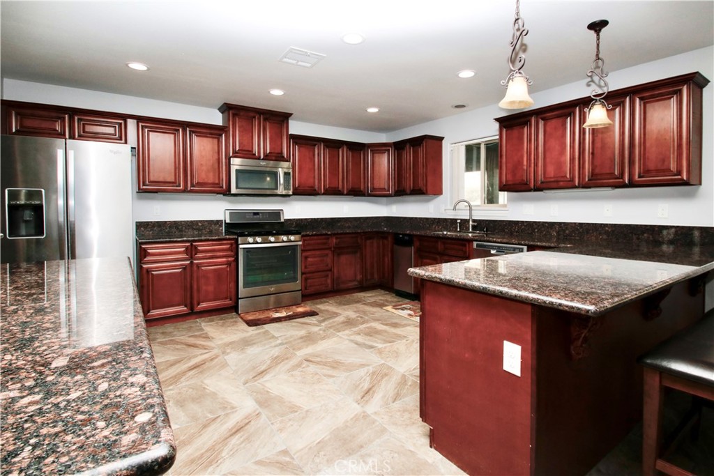 6202 Mandarin Road Yucca Valley, CA 92284 - Photo 11 of 24 a kitchen with wooden cabinets a sink a stove a refrigerator and a window