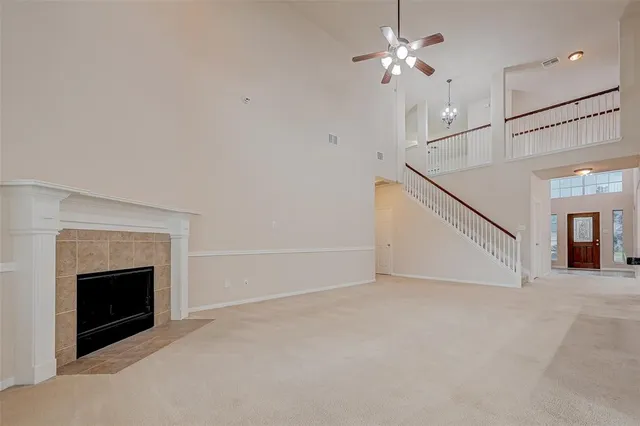 a view of an empty room with chandelier fan and fire place