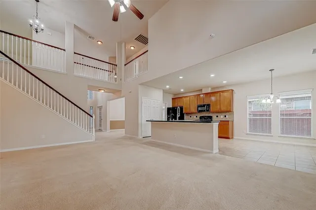 a view of an empty room and kitchen view with wooden floor
