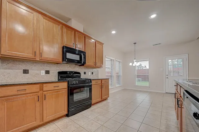 a kitchen with stainless steel appliances granite countertop a stove a sink and a microwave