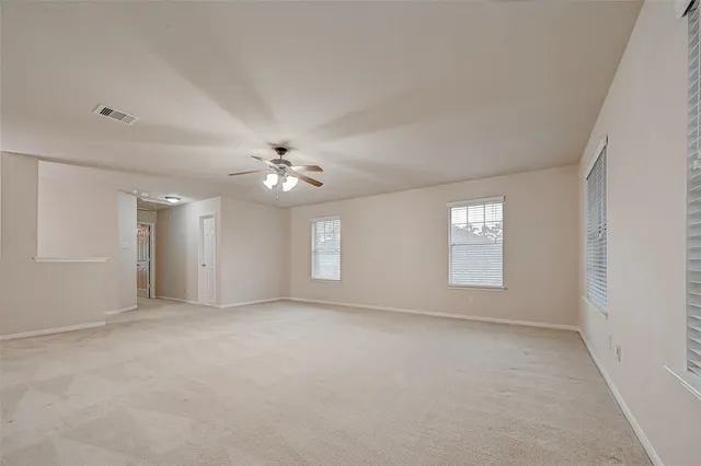 an empty room with windows and ceiling fan