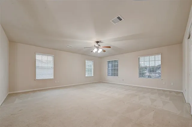 an empty room with chandelier fan and windows