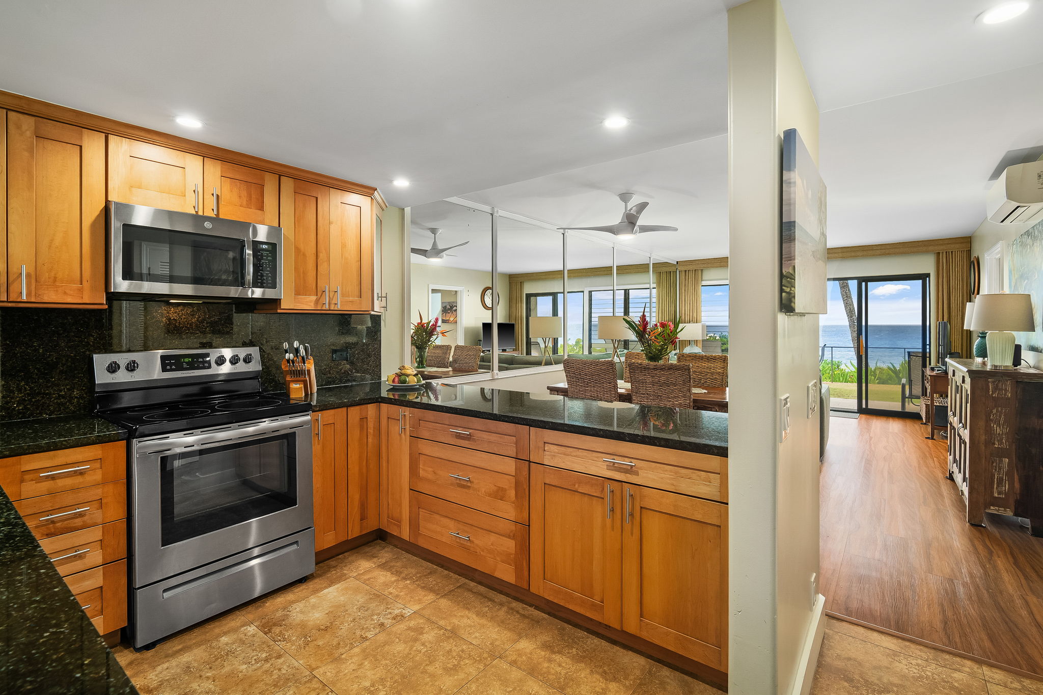 1775 Pe'e Road, Unit 101A Koloa, HI 96756 - Photo 6 of 25 a kitchen with stainless steel appliances granite countertop a stove top oven a sink dishwasher a refrigerator and a microwave