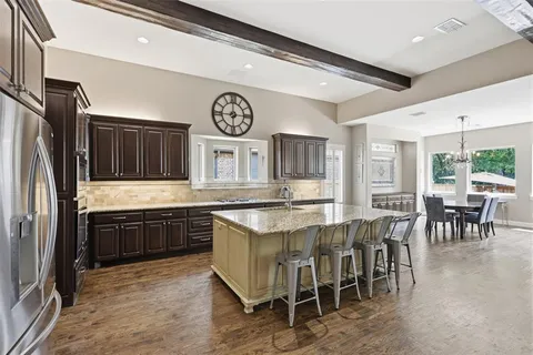 a kitchen with stainless steel appliances granite countertop a stove top oven a refrigerator and a dining table
