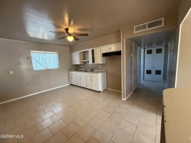 a kitchen with white cabinets a sink a stove a window and a potted plant