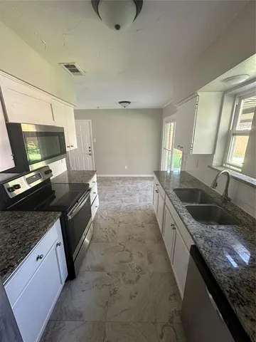 a kitchen with granite countertop a sink and a stove