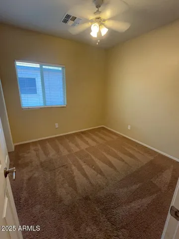 an empty room with closet and a chandelier fan