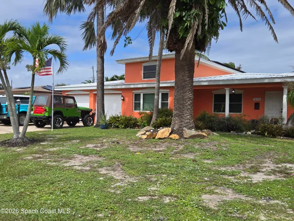 a view of a house with a yard and palm trees
