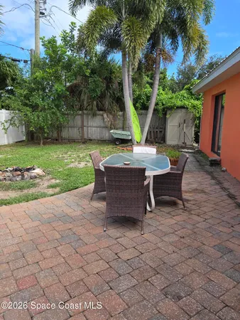 a view of a backyard with table and chairs potted plants and a large tree