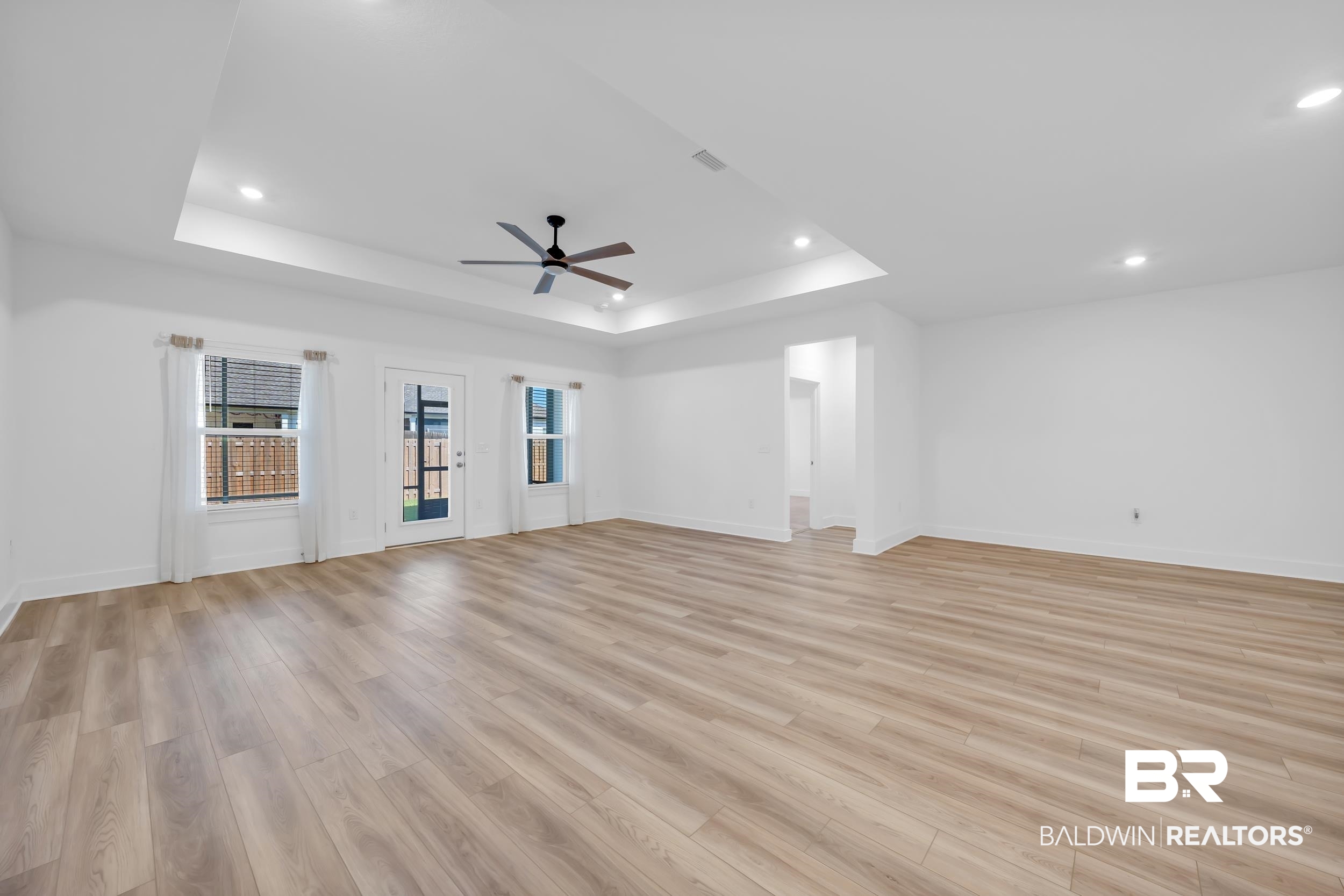 9933 Weller Cove Foley, AL 36535 - Photo 15 of 36 Spacious interior featuring wood-finish flooring, a tray ceiling with recessed lighting, and a dark-toned ceiling fan