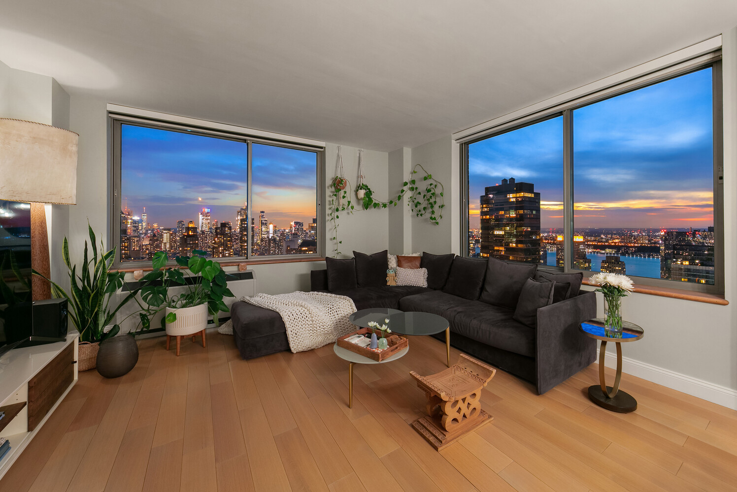 101 West 67th Street, Unit 52E Manhattan, NY 10023 - Photo 4 of 21 a living room with furniture potted plant floor to ceiling windows and a flat screen tv