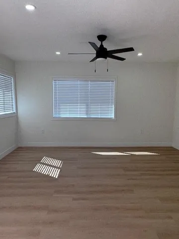 a view of a room with a ceiling fan and wooden floor
