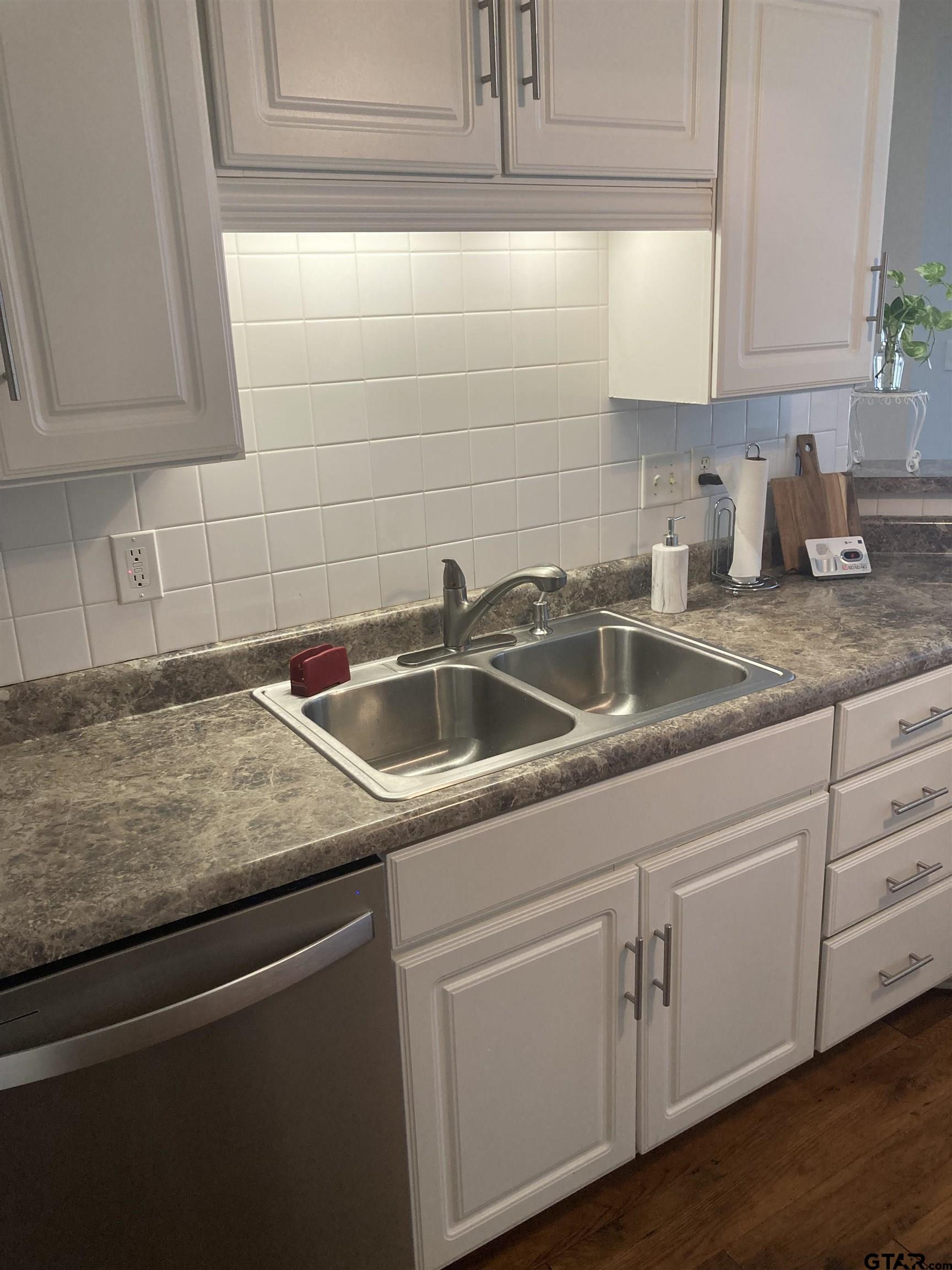 1521 Rice Road, Unit Q103 Tyler, TX 75703 - Photo 7 of 40 a kitchen with granite countertop white cabinets sink and dishwasher