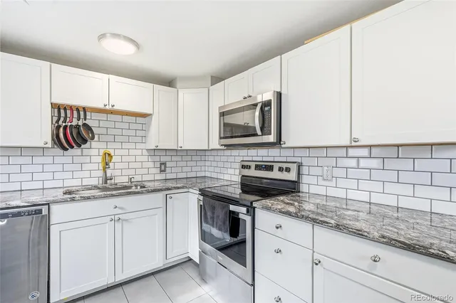 a kitchen with granite countertop white cabinets stainless steel appliances and a sink
