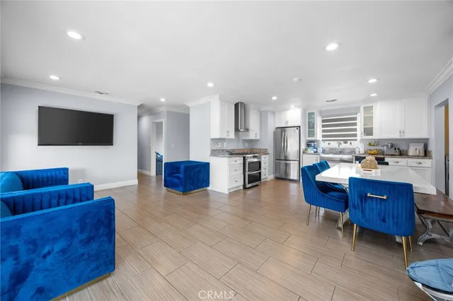 a living room with couches and kitchen view with wooden floor