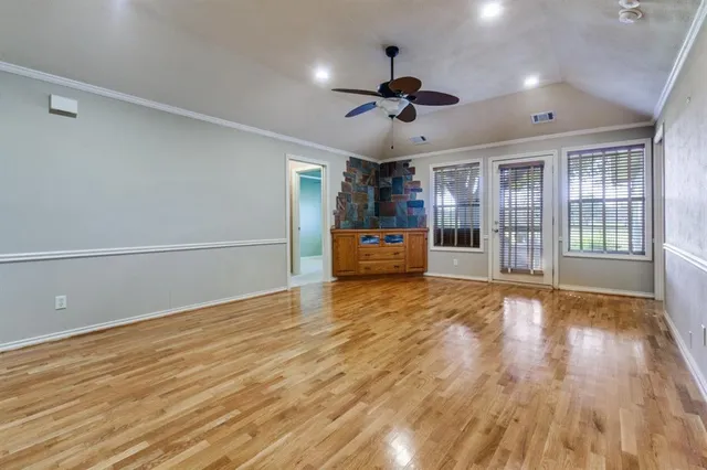 a view of an empty room with a window and wooden floor
