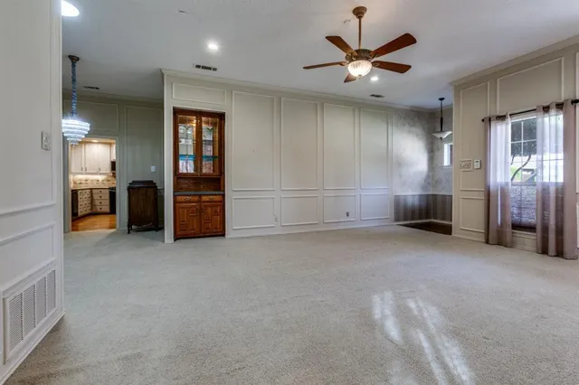 an empty room with chandelier fan and windows