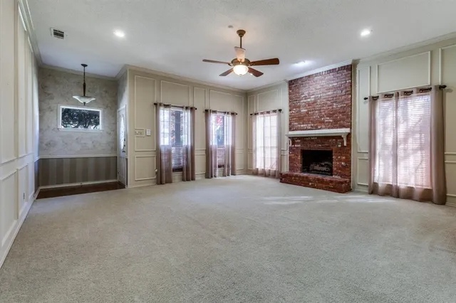 an empty room with fireplace cabinet and windows