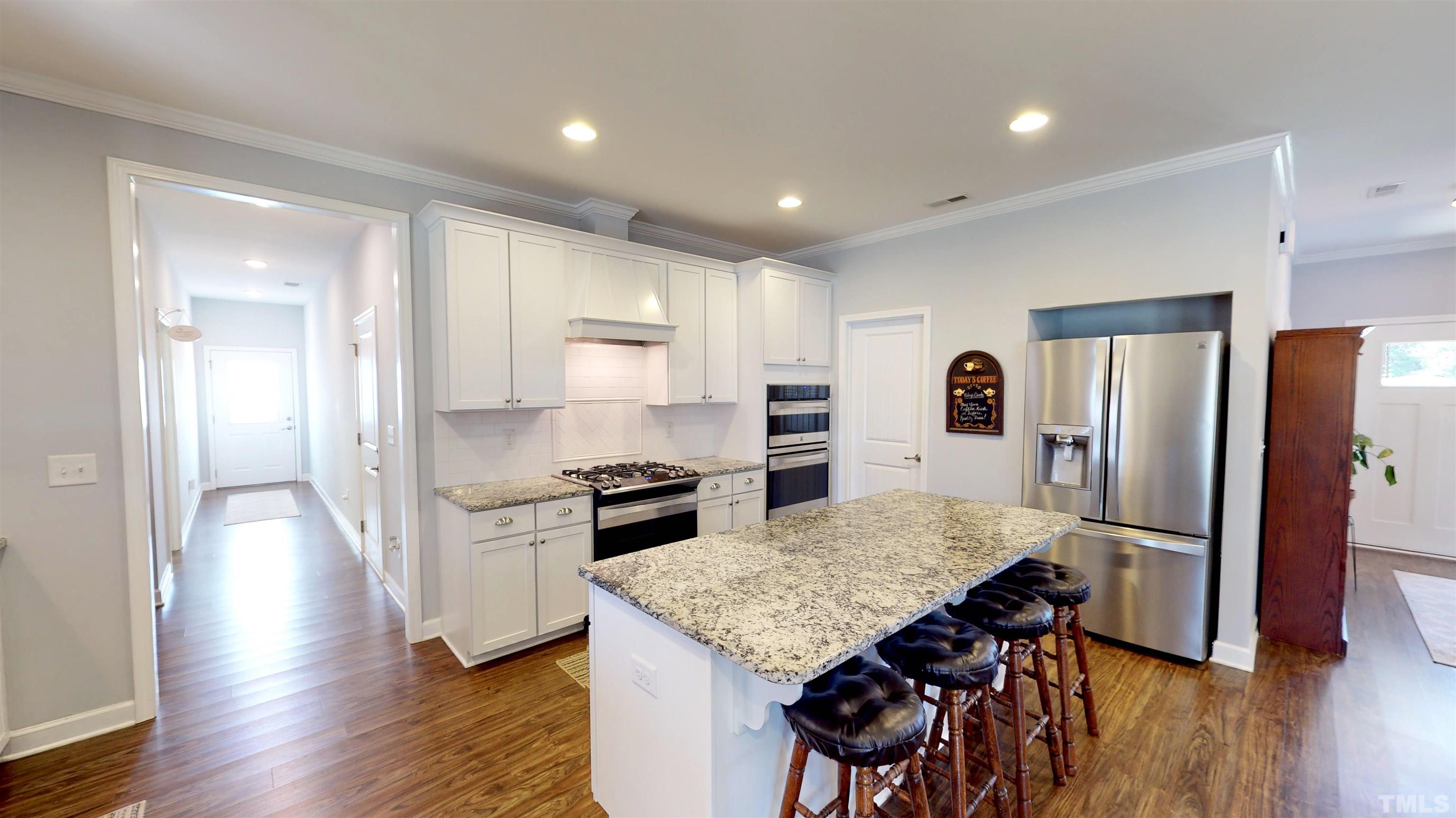 11250 Old Beulah Road Kenly, NC 27542 - Photo 21 of 66 a kitchen with stainless steel appliances granite countertop a stove a refrigerator a sink a dining table and chairs with wooden floor