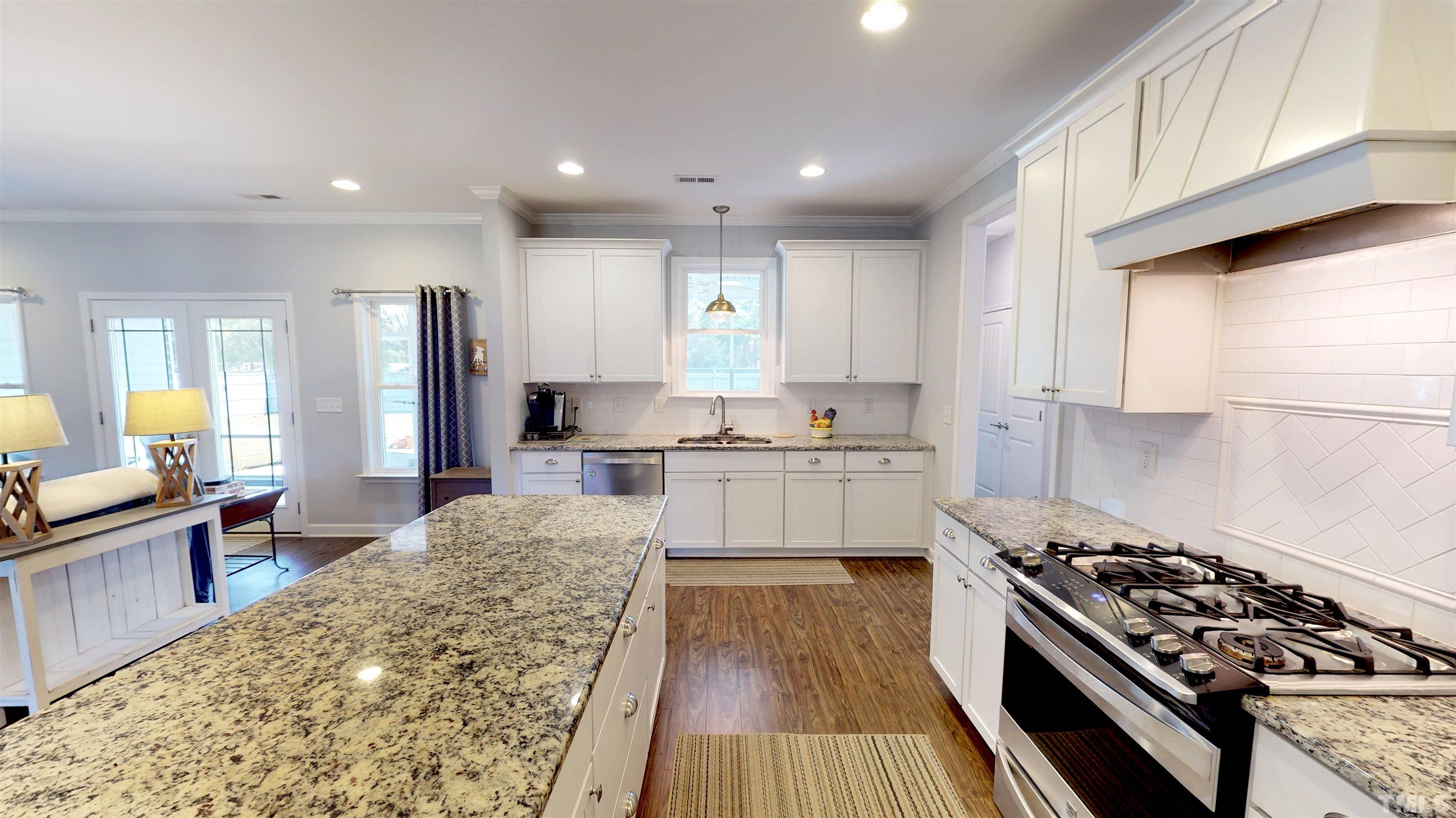 11250 Old Beulah Road Kenly, NC 27542 - Photo 26 of 66 a large kitchen with kitchen island a stove a sink dishwasher and white cabinets with wooden floor