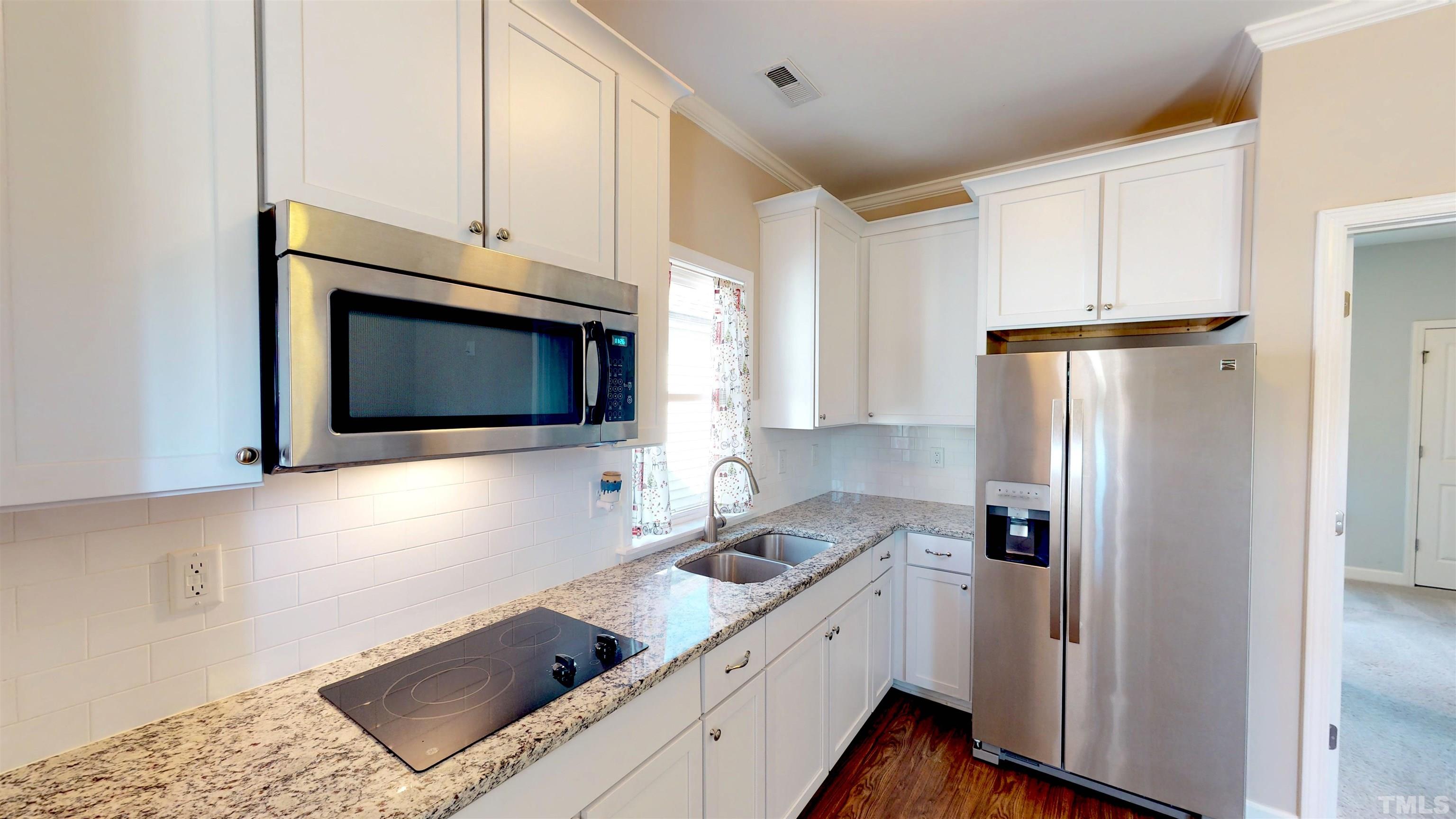 11250 Old Beulah Road Kenly, NC 27542 - Photo 51 of 66 a kitchen with white cabinets and stainless steel appliances