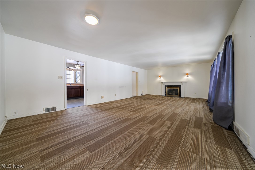 4602 College Road South Euclid, OH 44121 - Photo 2 of 26 Unfurnished living room with dark carpet, ceiling fan, and a glass covered fireplace