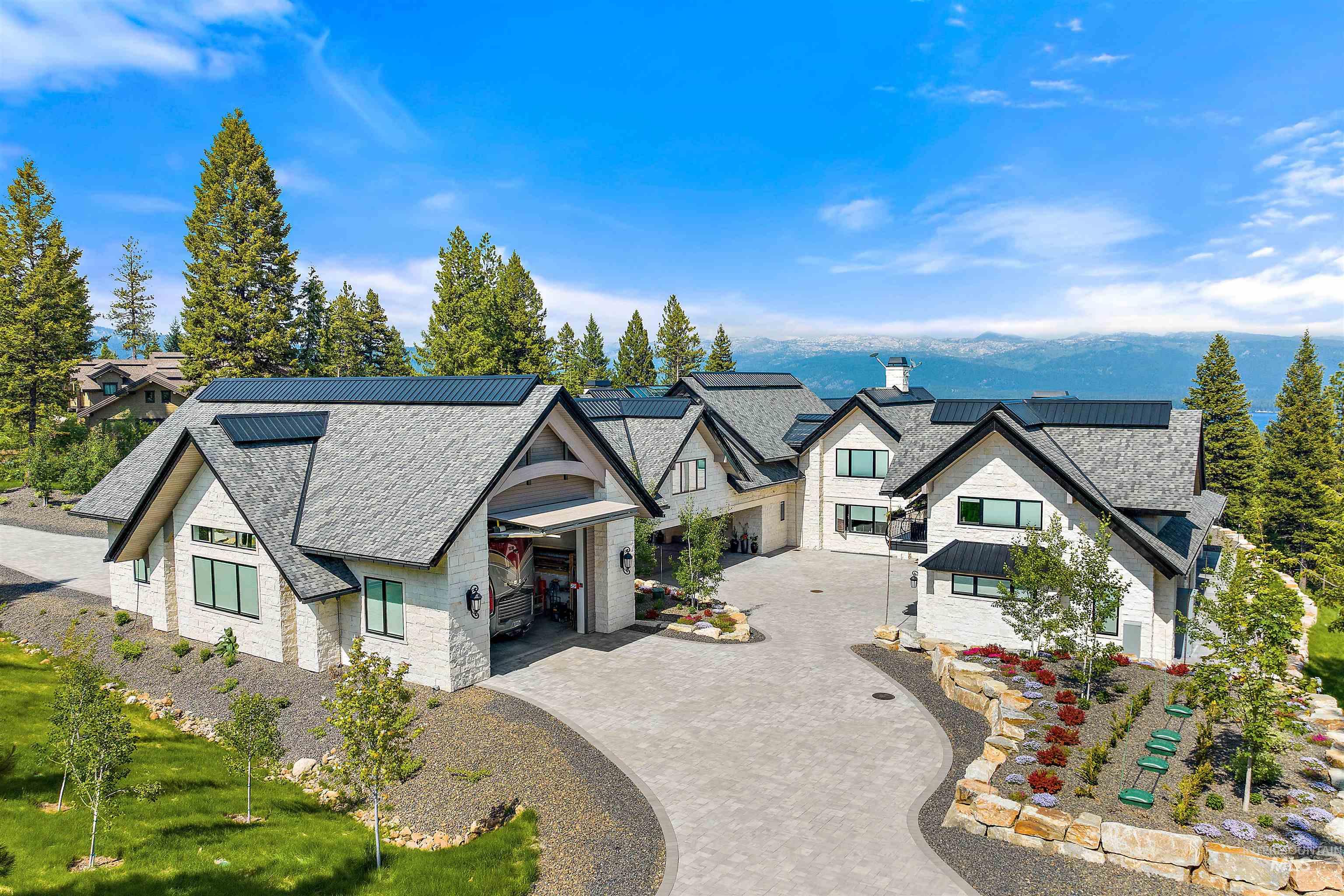 649 Migratory Rdg Way McCall, ID 83638 - Photo 2 of 44 Expansive property featuring a multi-gabled residence with light-colored stone and siding, dark-toned roofing, and a substantial paved driveway