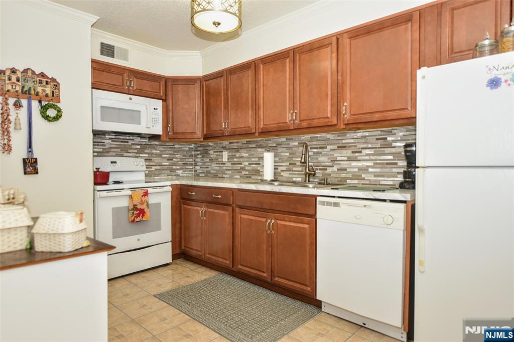 125 Prospect Avenue, Unit 3J Hackensack, NJ 07601 - Photo 15 of 25 a kitchen with stainless steel appliances granite countertop a sink a stove a refrigerator a washer and dryer with wooden floor