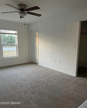 an empty room with windows and fan