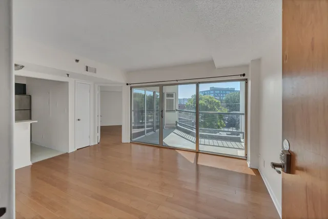 a view of empty room with wooden floor and fan