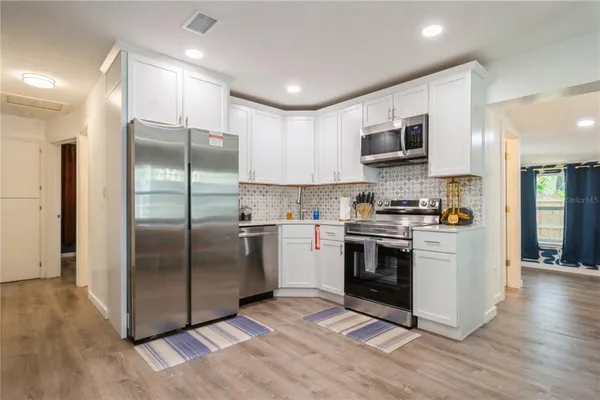 a kitchen with stainless steel appliances cabinets a sink and a wooden floor