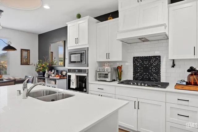 a kitchen with stainless steel appliances a sink a stove and cabinets
