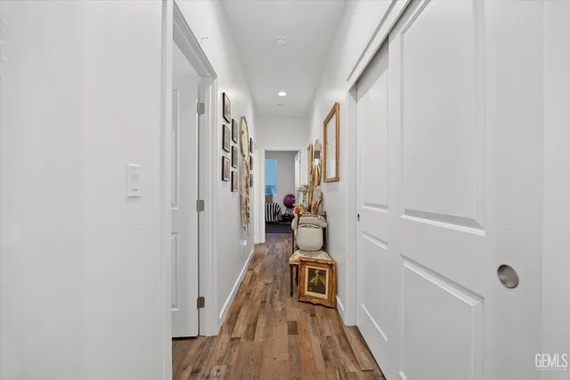 a view of a hallway with wooden floor and a bathroom
