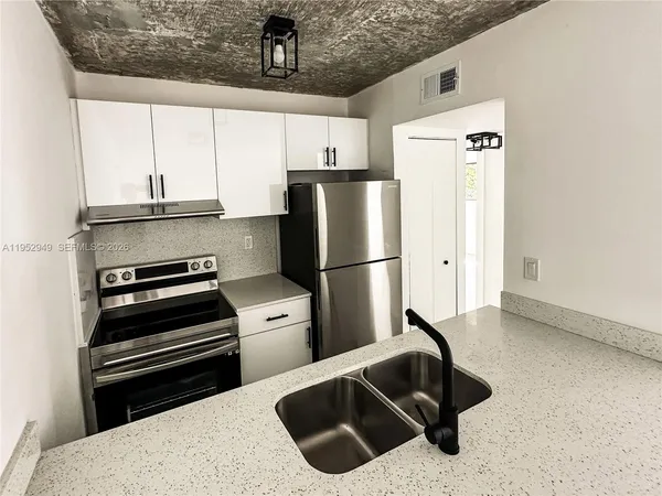 a kitchen with granite countertop a refrigerator and a sink