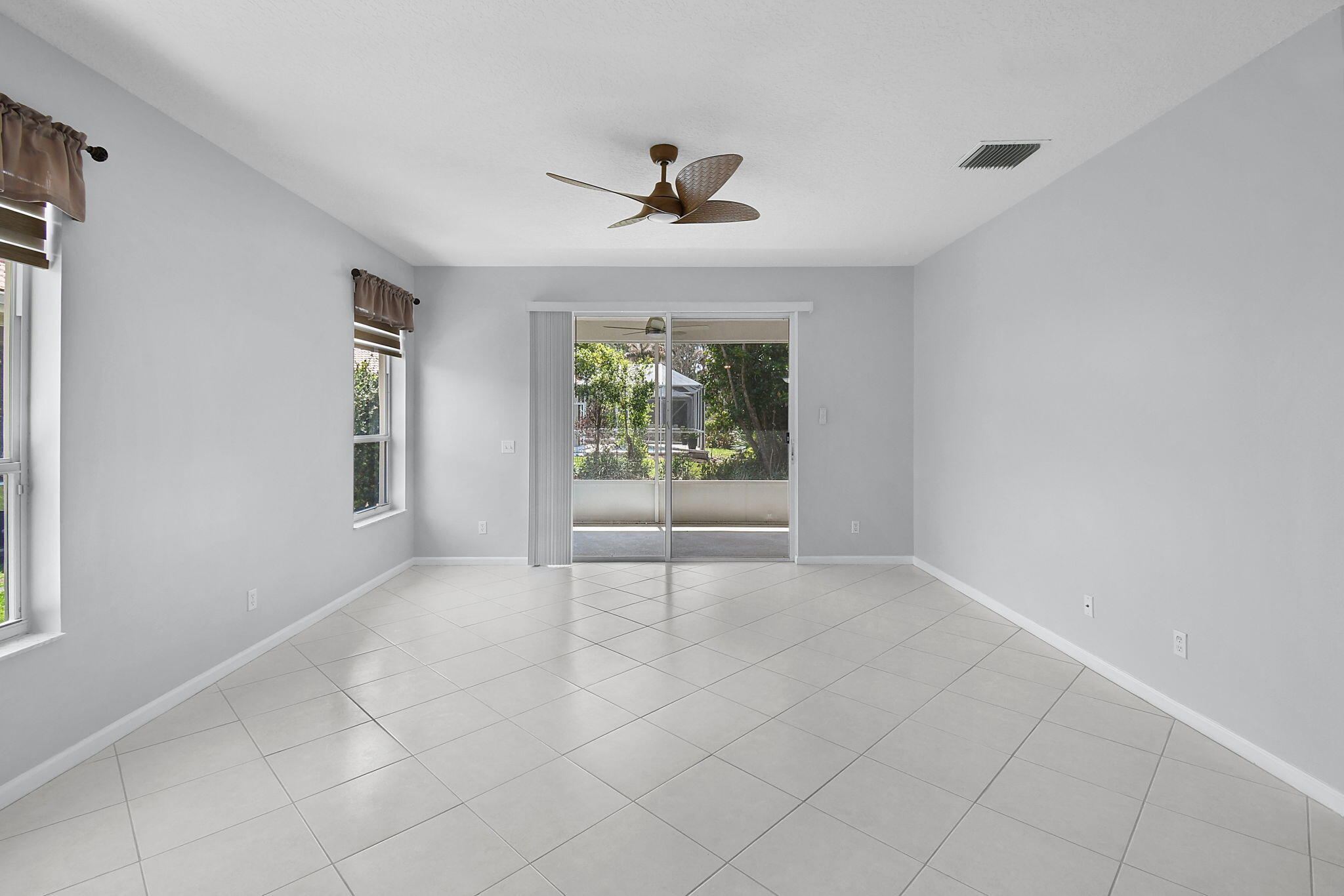 6785 Southeast Warwick Lane Stuart, FL 34997 - Photo 5 of 62 an empty room with windows and ceiling fan