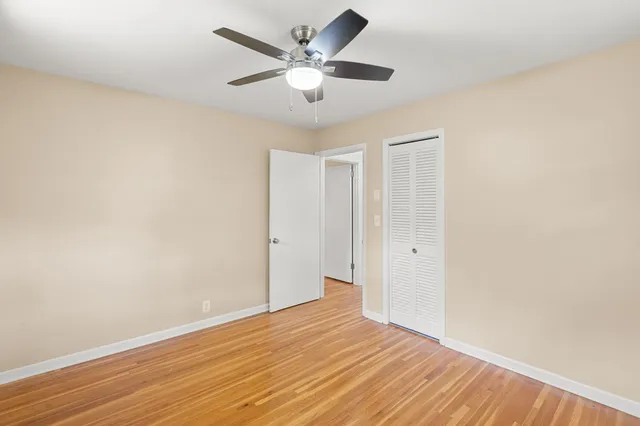an empty room with wooden floor and ceiling fan