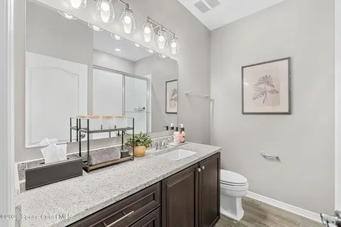 a bathroom with a granite countertop sink a large mirror and toilet