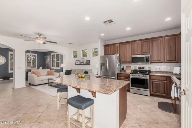 a large kitchen with kitchen island granite countertop a stove top oven a sink a dining table and chairs