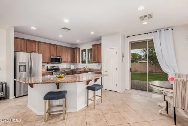 a kitchen with stainless steel appliances kitchen island granite countertop a refrigerator and a stove top oven