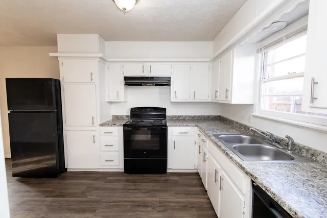 a kitchen with granite countertop a refrigerator stove and sink