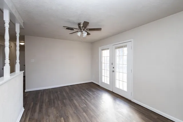a view of empty room with wooden floor and fan