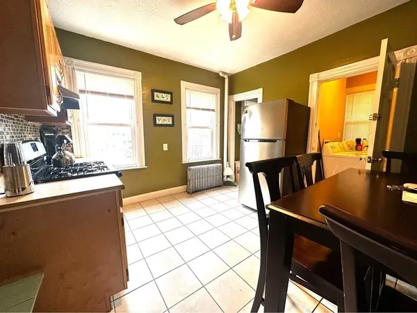 a kitchen with stainless steel appliances granite countertop a stove a refrigerator a dining table and chairs with wooden floor