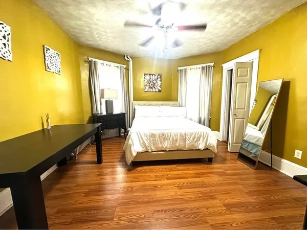 a spacious bedroom with a bed and wooden floor