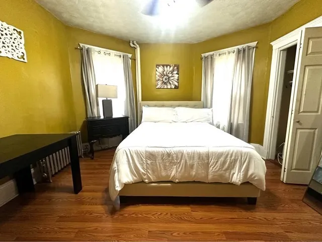 a spacious bedroom with a bed and wooden floor